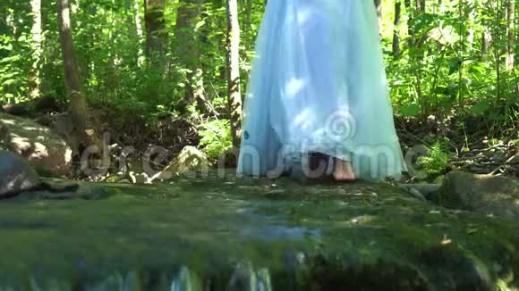 行走的女人在野生丛林森林里旅行穿着连衣裙踏着干净的山河视频的预览图