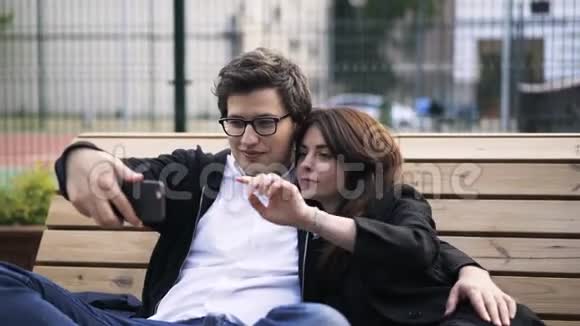 一对情侣在网球场附近的长凳上自拍视频的预览图