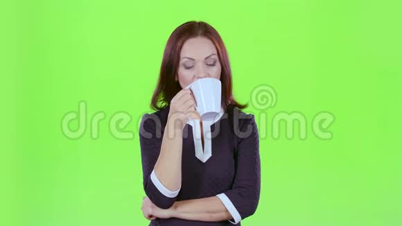 拿着一杯茶的女人看着远处想着自己的事情绿色屏幕视频的预览图