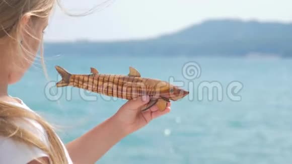 一个孩子正在大海的背景上玩玩具鱼视频的预览图