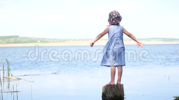 小女孩穿着裙子张开双臂站在湖边视频的预览图