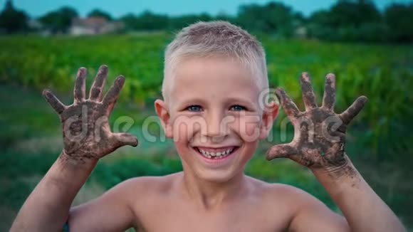 一个快乐的孩子从泥土中露出肮脏的双手一个涂抹在泥土中的男孩一种快乐的童年消遣视频的预览图