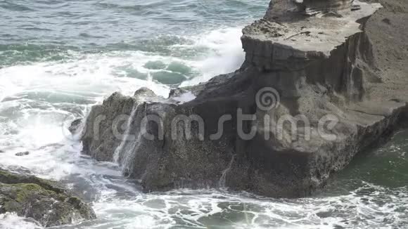 热带海洋的海岸在阳光明媚的日子里波浪在海岸上流淌着黑色的石头缓慢的运动视频的预览图