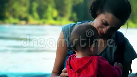 妈妈和宝宝坐在河岸上拥抱视频的预览图