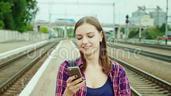 一个漂亮的年轻女子沿着铁路站台走使用手机理念是成功的商务旅行视频的预览图