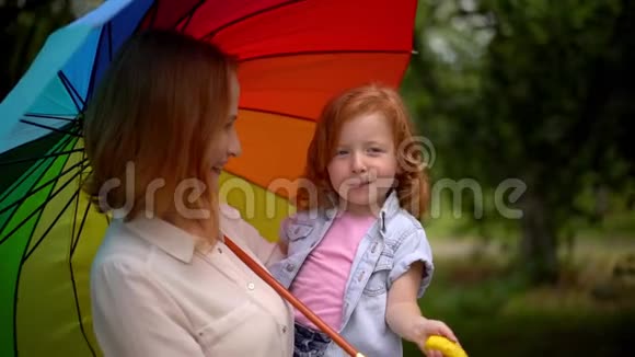 妈妈和女孩在大自然的彩伞下视频的预览图