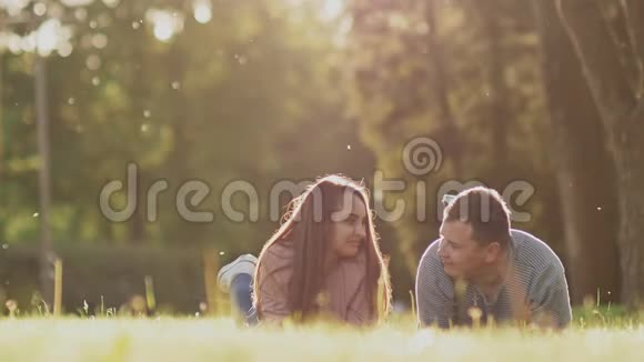 夏日绿茵上的浪漫情侣他们仰着脚躺在肚子上在阳光下快乐在一起视频的预览图