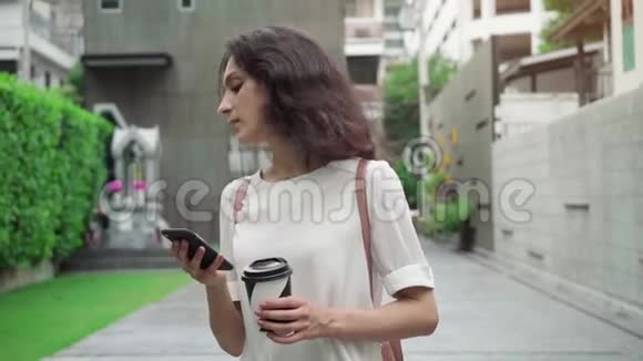 女孩走在城市街道上喝着咖啡以超慢的速度前进视频的预览图