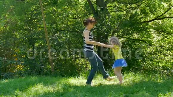 积极快乐的家庭一起在公园享受阳光温暖的一天年轻的布鲁内特母亲把她的女儿团团转视频的预览图