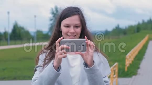 年轻女子在操场上用手机拍摄视频视频的预览图