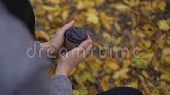 孤独的人用热饮料温暖冻僵的手在寒冷的秋天心碎视频的预览图