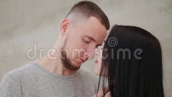 一对相爱的夫妇在混凝土墙的背景下拥抱和亲吻视频的预览图
