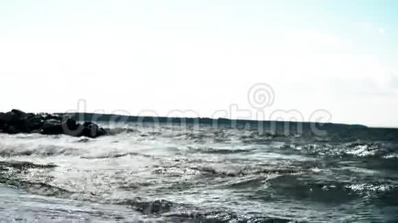 年轻人在海洋中风筝冲浪强烈的海浪拍打着石头视频的预览图