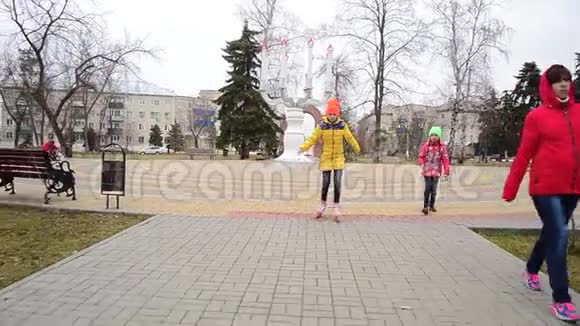 女孩在公园的铺面公路上学溜冰鞋公园的家庭度假视频的预览图