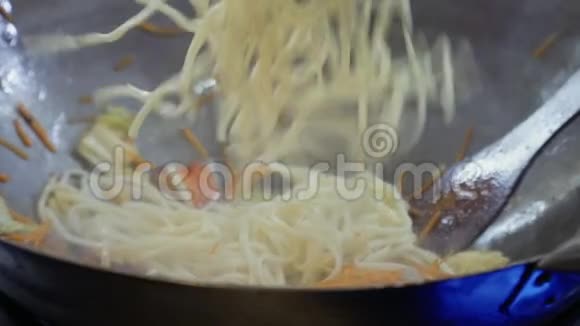 厨师把乌冬面和炒蔬菜放进热锅里视频的预览图