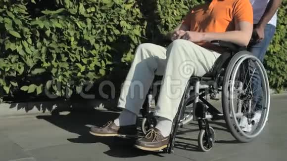 一个好男人和一个坐在轮椅上的男人走在一起视频的预览图
