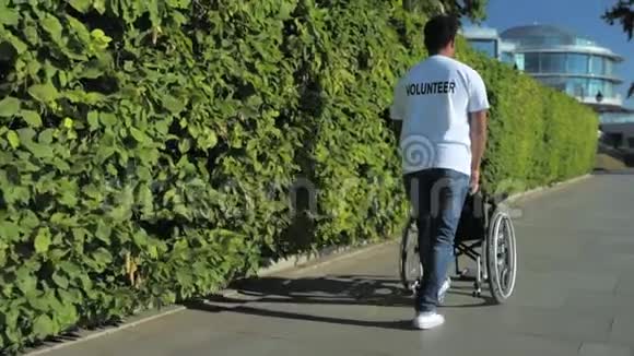 仁慈的志愿者推着轮椅的后景视频的预览图