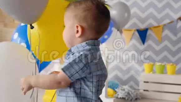 一个快乐的蹒跚学步的孩子笑着被气球包围着视频的预览图