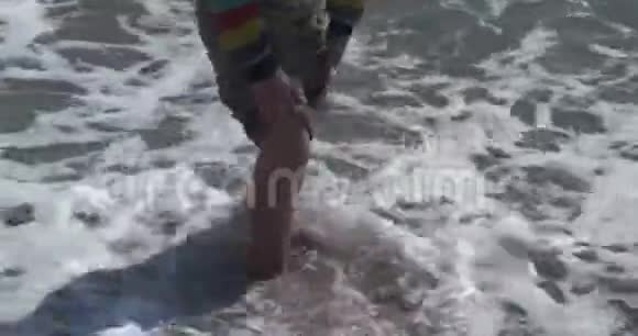 这个男孩脚在海里这孩子正在尝试海水的温度视频的预览图