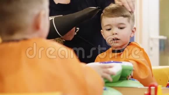 儿童发型理发师在理发店和小男孩一起工作视频的预览图