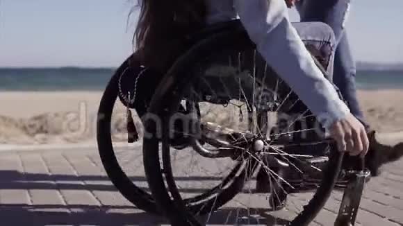 家庭休闲坐轮椅的年轻残疾妇女和她的母亲在海边散步说话玩得很开心视频的预览图