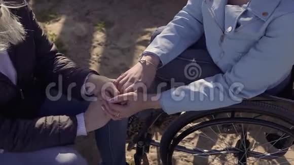家庭休闲坐在轮椅上的残疾青年妇女与坐在海边的母亲说话抱着她视频的预览图
