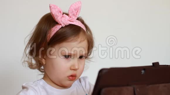 特写肖像有趣的孩子看在电脑屏幕上播放下载的应用程序一个可爱的小女孩视频的预览图