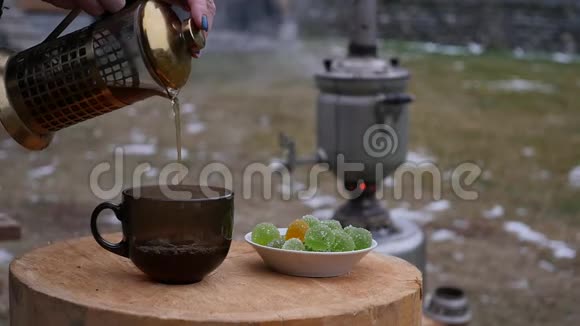 在寒冷的季节在后院的一个杯子里倒茶大的旧萨莫瓦尔慢动作视频的预览图