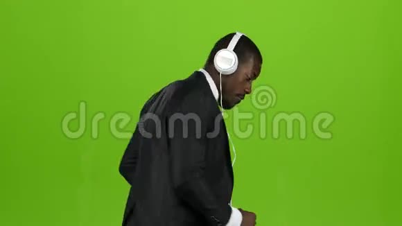 商人戴着耳机现场听音乐跳舞绿色屏幕视频的预览图