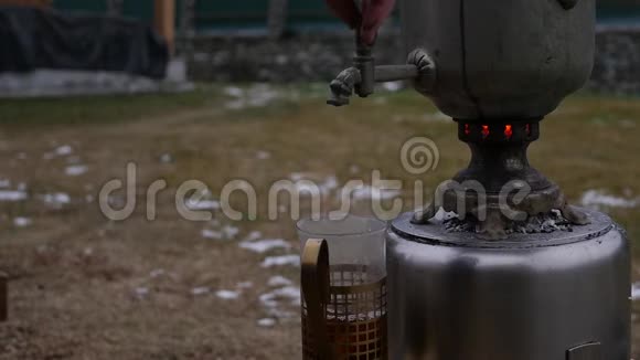 在寒冷的季节在后院的一个杯子里倒茶大的旧萨莫瓦尔慢动作视频的预览图