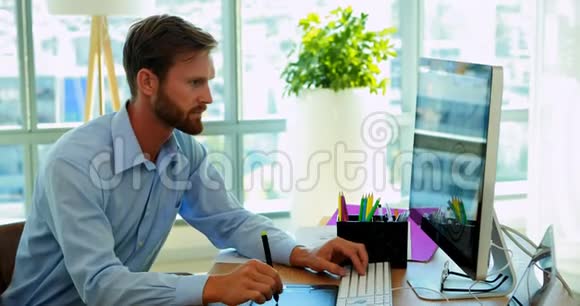 男性平面设计师在她的办公桌上做平面平板电脑视频的预览图