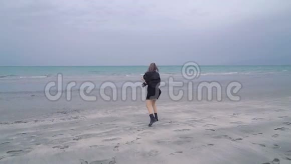 幸福美丽的金发女人沿着海滩散步寒冷的雨天秋天少女潮人或朋克在视频的预览图