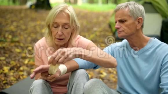 有爱心的老妇人用绷带包扎丈夫的手视频的预览图
