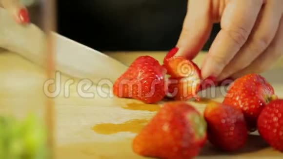 一个女人正在用刀子在木板上用刀切一个成熟的草莓视频的预览图
