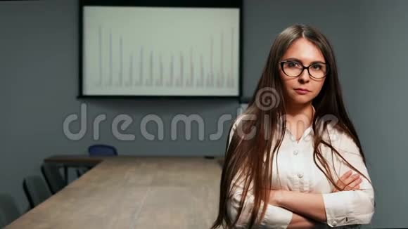 戴着眼镜坐在会议室里看镜头的漂亮女孩的画像视频的预览图