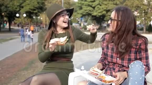 有趣的女孩花时间在公园里笑着吃三明治三明治日假日视频的预览图