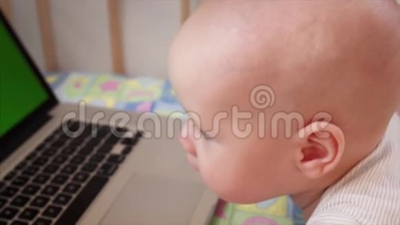 6个月大的男孩在床上玩手提电脑的慢镜头画像视频的预览图