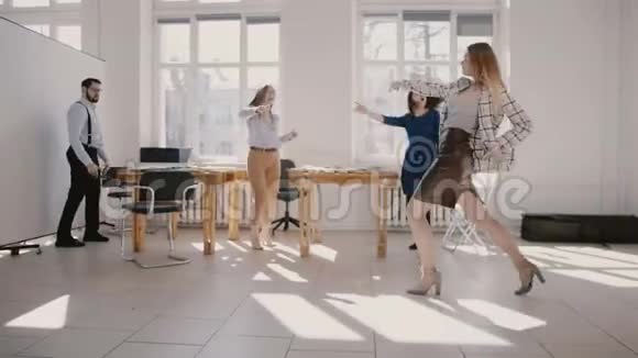 年轻的疯狂女商人和多民族的同事一起跳舞庆祝团队事业的成功慢动作视频的预览图