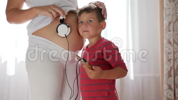 孩子把耳机放在孕妇肚子上婴儿在肚子里听音乐视频的预览图