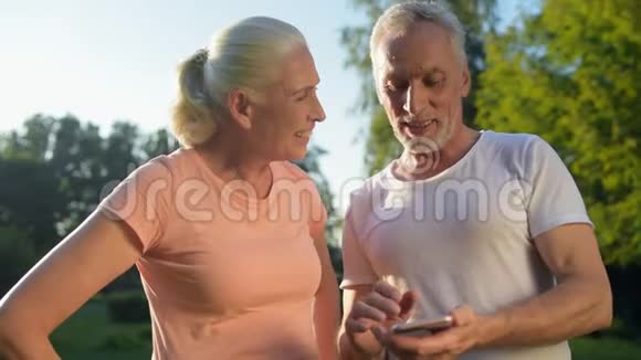 快乐的老夫妇在公园里用手机视频的预览图