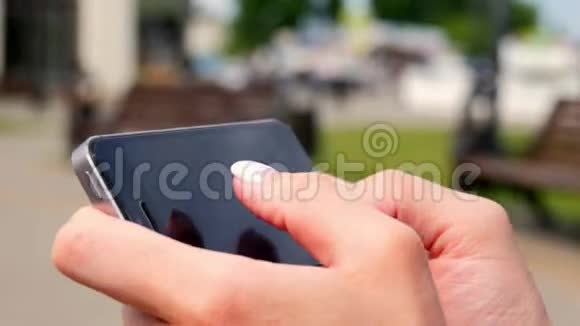 年轻漂亮的女人在公园的手机上拨一条短信女子手拨电话短信的特写视频的预览图