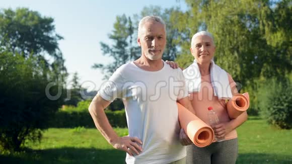 快乐的老夫妇站在公园里拿着练习垫视频的预览图