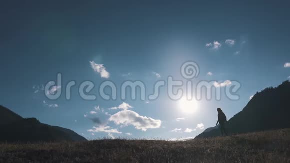一个旅行者在山峦和天空背景下的剪影那个旅游女孩正沿着山顶走视频的预览图
