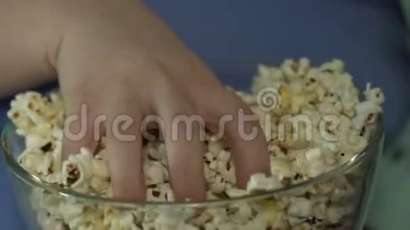 胖孩子把一把爆米花从碗里拿出来吃把它撒在周围视频的预览图