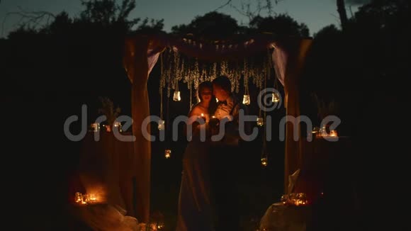 幸福的一对新婚夫妇手里拿着蜡烛看着对方的眼睛爱站在下面视频的预览图