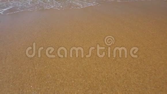 泡沫海浪随着金色的沙子快速地滚到海岸上冲刷着大海视频的预览图