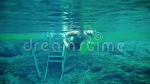 肌肉男在清澈的蓝色湖水中潜游视频的预览图