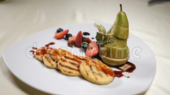 餐厅女性用叉子烤奶酪吃用梨子和浆果切片装饰的白色盘子慢动作视频的预览图
