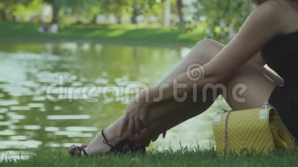 疲倦的女孩坐在池塘边在绿草上放松视频的预览图