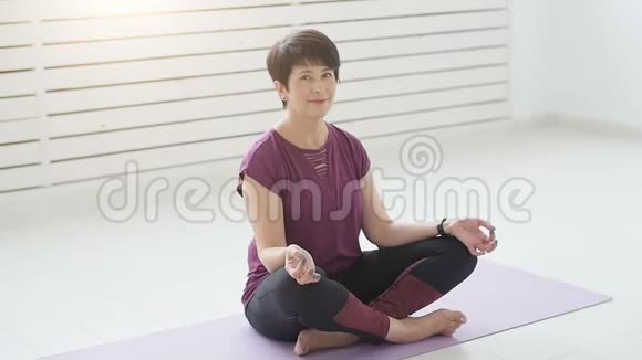 中年瑜伽迷在室内练习瑜伽视频的预览图